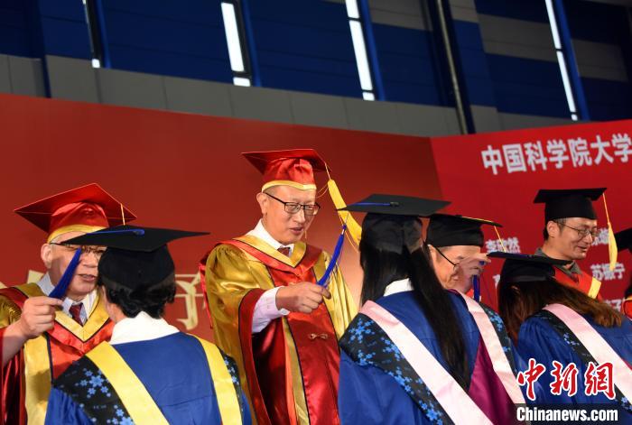 中科院副院长、国科大校长周琪院士为获得国科大学位学生代表扶正流苏。  中新社记者 孙自法 摄