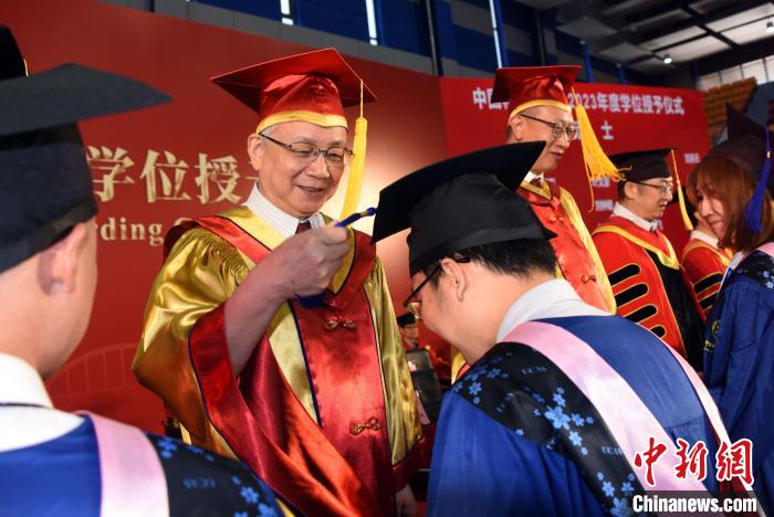 中科院院长侯建国院士为获得国科大学位学生代表扶正流苏。  中新社记者 孙自法 摄